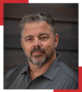 Man with salt and pepper beard and hair in a grey polo